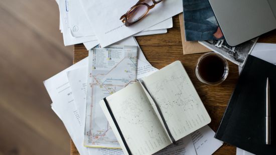 a table with a notebook and map along with a coffee mug