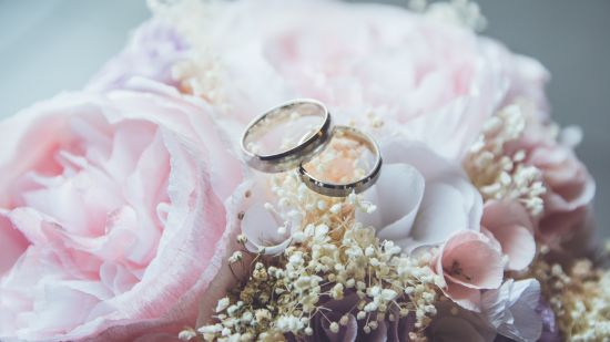 a pair of rings kept on a bouquet of white and pink flowers 