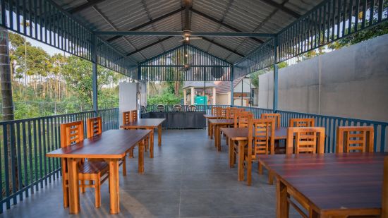 Dining area with wooden tables and trees at Feel Free Retreat, Wayanad