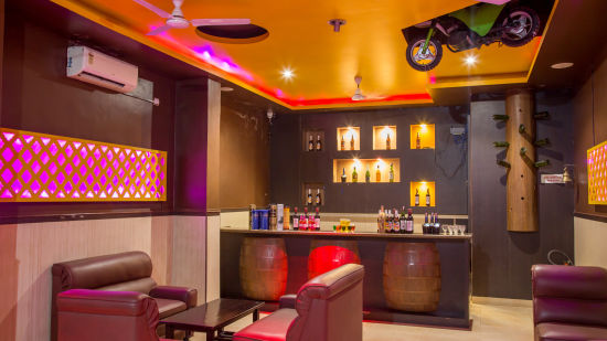 The bar counter showing different different drinks available with sofas near it at Pink Fly - Hotel Shompen