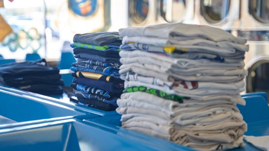 clothes folded in whites and coloured with front load washing machines in the background