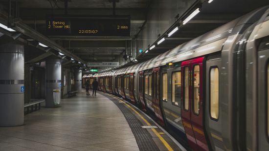 An underground train station platform with a train and electronic timetable displays