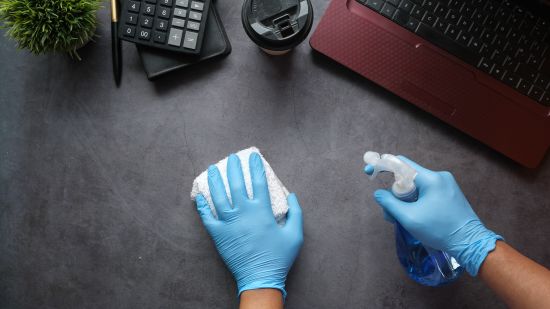 closeup view of a hand in blue gloves cleaning a table