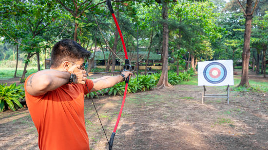 A man with a bow and arrow, aiming at the target