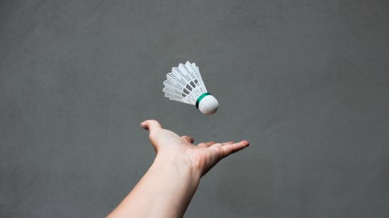 a person throwing a shuttlecock before a serve