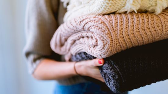 a woman carrying a pile of warm clothes for laundry