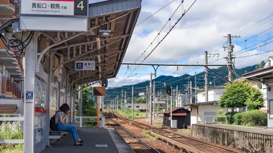 an image of a railway station situated closer to a hill station and captured with a girl waiting for a train