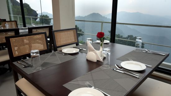 Chairs and tables with cutlery on them, beside a glass window