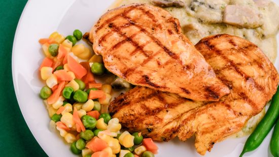 grilled chicken on a plate with some veggies