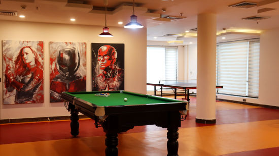 a pool table inside the kids zone with art work on the wall and a light shining on the pool table - Rosetum Kasauli