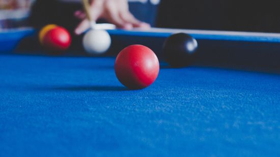 A person looking to pot a red ball playing snooker 