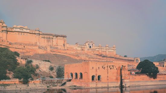 Amer fort building on the bank of a water body built with yellow and pink sandstone