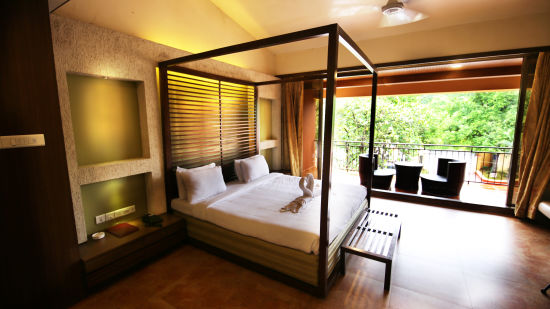 a king size bed in the bedroom with the door opening up to the outside sit-out area - Zara's Resort