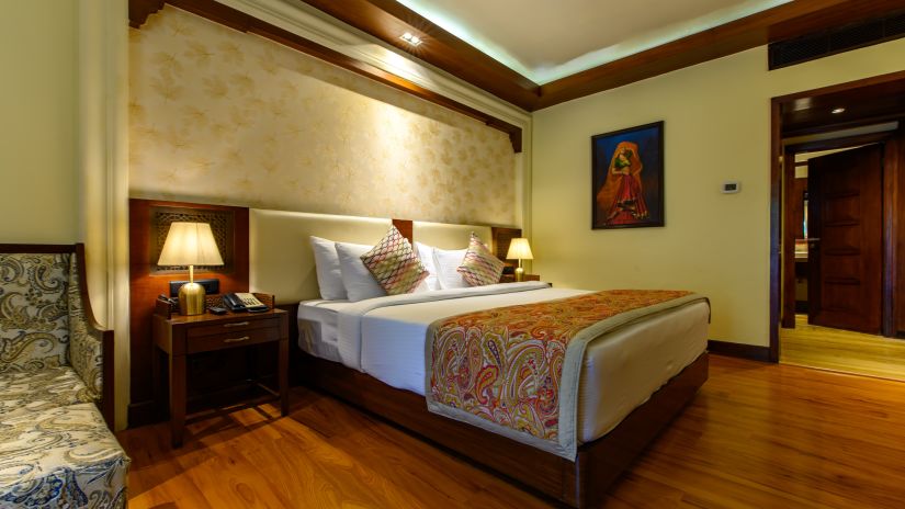 The interiors of our Premium Cottages in Pushkar featuring a balcony, a comfotable bed, sofa chairs 139