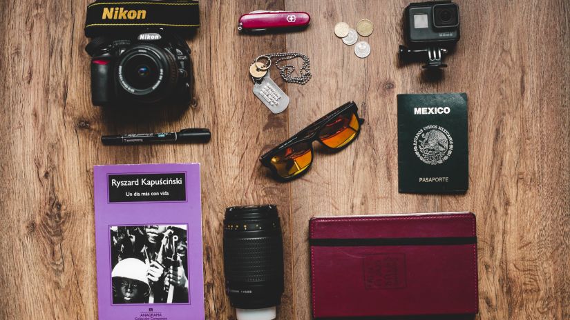 an image showcasing various travel essentials like a journal, camera, sunglasses, a passport, etc. 