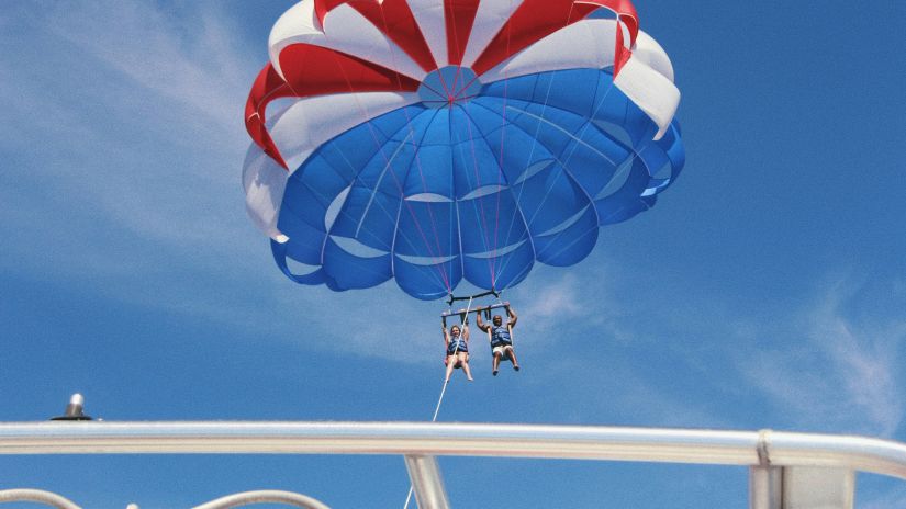 Two people parasailing as seen from the boat with the rope attached