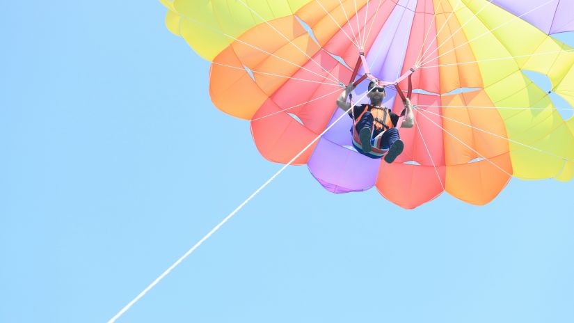 A view from below of a person parasailing with the rope seen as well - Havelock Parasailing