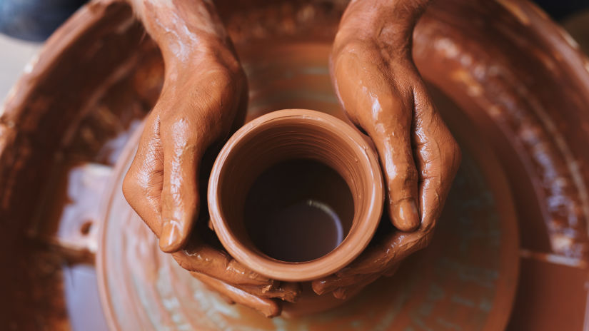 an image of a hand moulding a mug out of clay