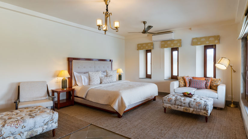 A king bed with side tables, lamps and sofa opposite it inside a room - Chunda Shikar Oudi, Udaipur