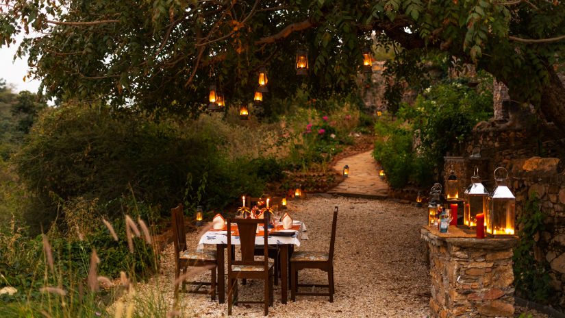 a table for four set up next on a pathway with forest cover surrounding it - Chunda Shikar Oudi, Udaipur