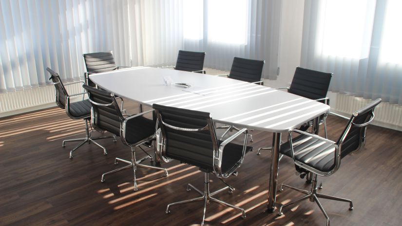 A conference room with a white table and black office chairs