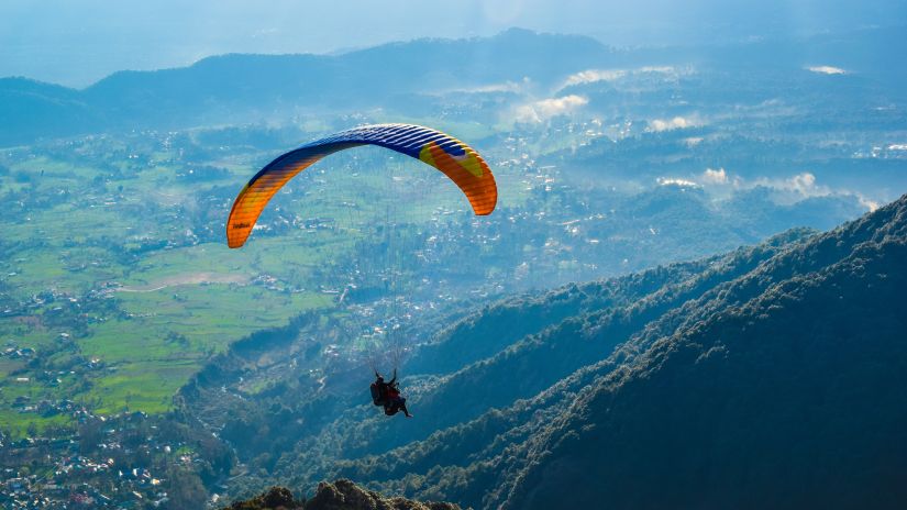 Digantaa Resort - a person paragliding amid mountains