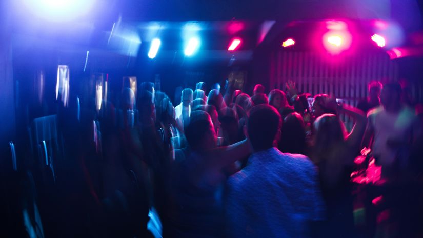 A blurry image of a crowded dance floor with blue and red lights