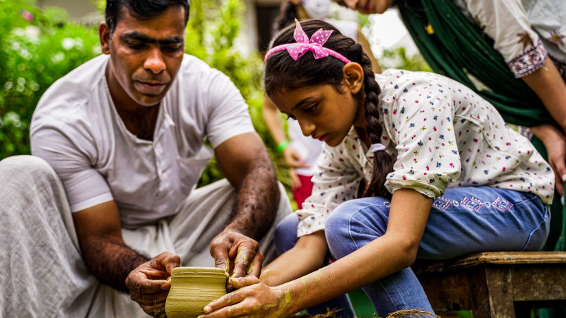 A pottery instructor teaching the art to a girl who is in working on a pot - Heritage Village, Goa