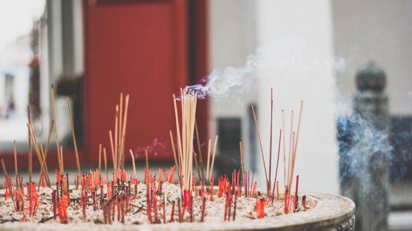 Incense sticks with smoke coming out of them in a temple