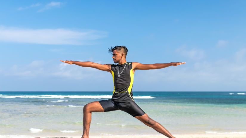 a man in a yoga pose on the beach