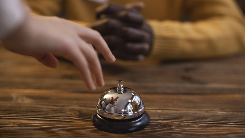 a person about to ring a reception desk bell