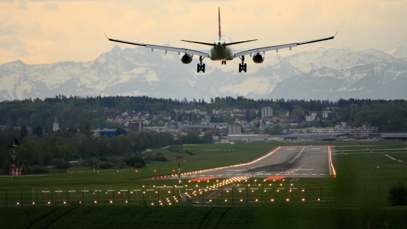 an aeroplane landing on the runway with greenery surrounding it 