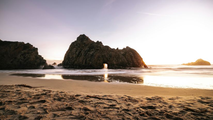 Beach with large rock formations in the backdrop on a sunny day