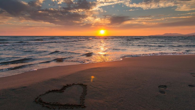 Heart drawn on a beach at sunset