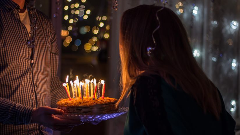 Karma Lakelands - a person holding a cake while another is blowing out the candles on it