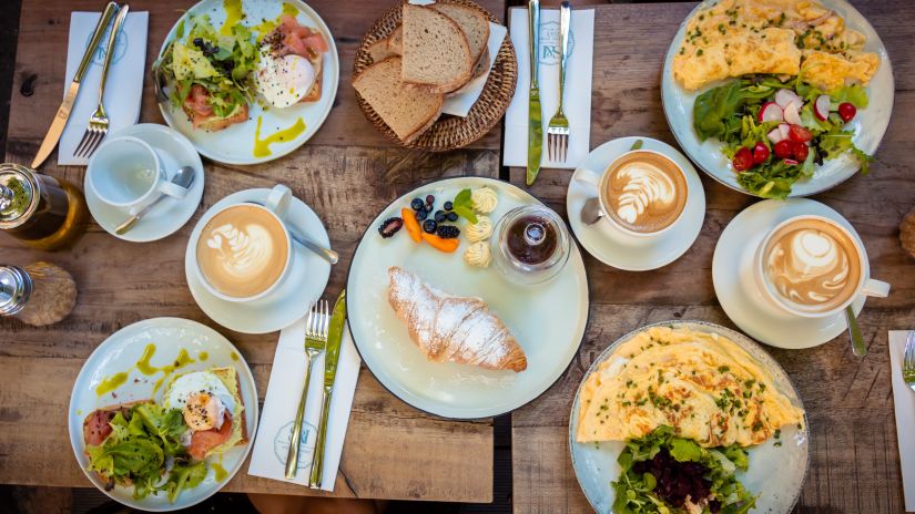 A table with a spread of breakfast items with hot beverages