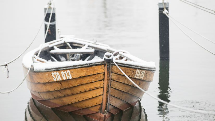 a wooden boat tied on to two wooden logs to not let it wander on the river