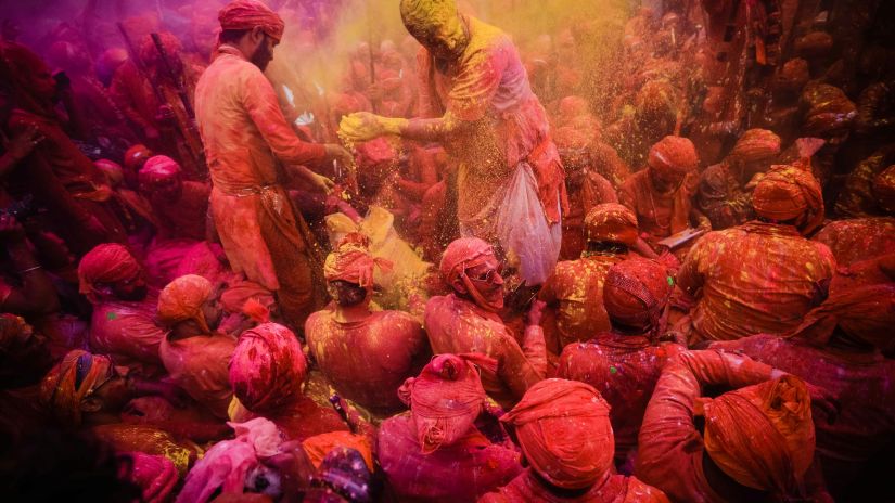 a group of people climbing on top of each other and performing a ritual with a crowd below them