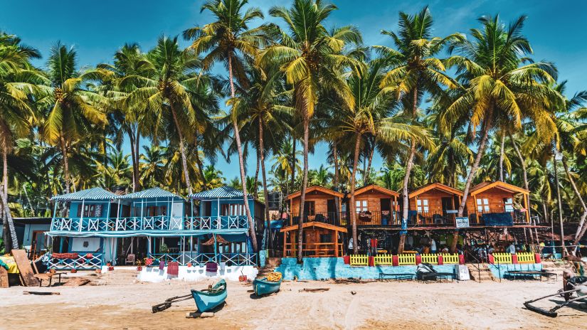 colourful shacks lined on a beach with trees in the surroundings