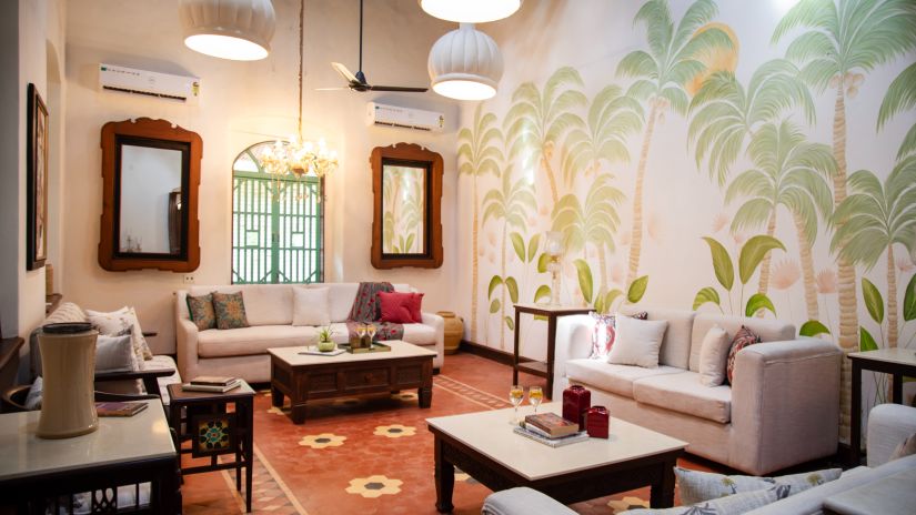 white room with tables and couches with green trees drawn on the walls  @ Lamrin Ucassaim Hotel, Goa