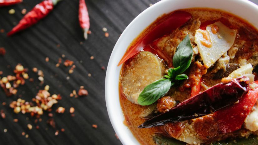 a bowl of fish curry as seen from above with dry chillies on the side