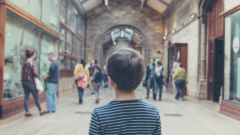 a child looking at people inside a museum 