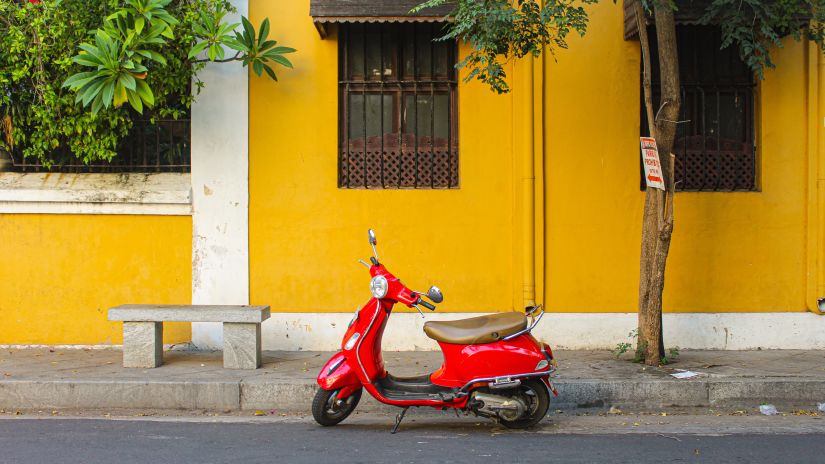 a red scooter parked in front of a yellow building