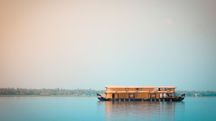 A house boat travelling on the kochi lake with clear skies in the background