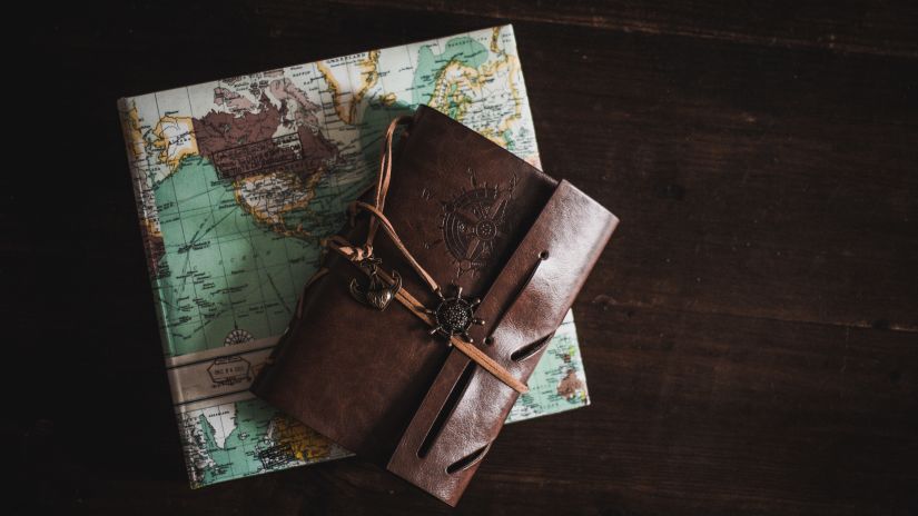 brown leather book kept on the top of a map