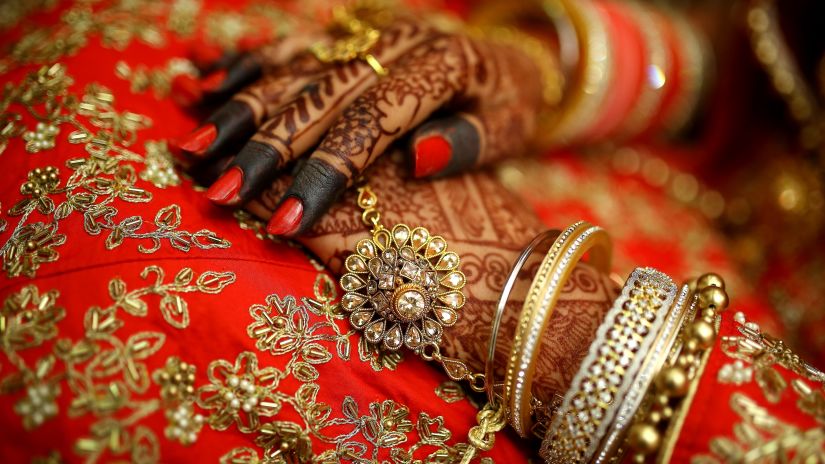 A bride sitting in her wedding saree and mehendi in her hands