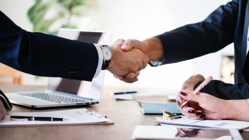 businessmen shaking hands over a desk 