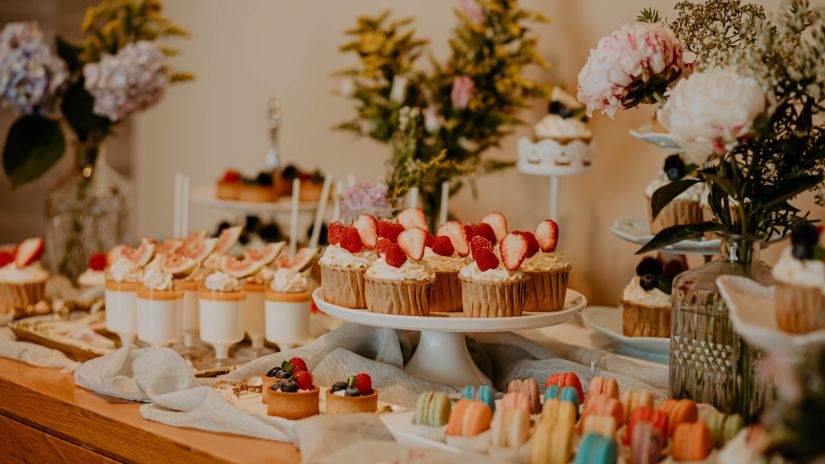 desserts station with many types of desserts kept on a table at a buffet