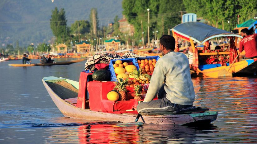 a person selling fruits on a boat in middle of the lake