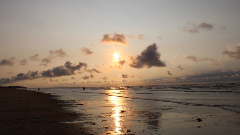 a view of the setting sun with few clouds in the sky and the reflection of the sun on the water of Mandarmani beach - Mandarmani Best Time to Visit